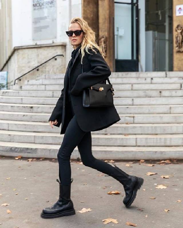 un look totalement noir avec un pull, des skinnies, des bottes de combat, un manteau court et un sac